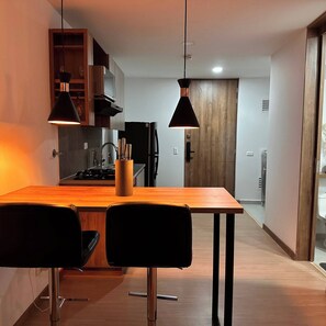 Eine moderne Küche mit einem Holztisch, zwei schwarzen Stühlen und Pendelleuchten.