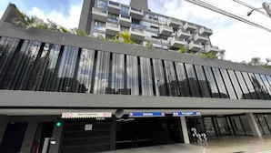A modern building with a flat roof, large windows, and a storefront with signage. - Premium Loft with AC  Panoramic View in Laureles (Medellín)