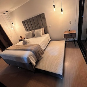 A modern bedroom with a bed, bedside tables, and a nightstand. - Premium Loft with AC  Panoramic View in Laureles (Medellín)