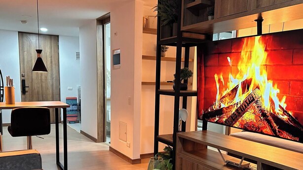 A modern living room with a fireplace, a dining area, and a kitchen in the background. - Premium Loft with AC  Panoramic View in Laureles (Medellín)
