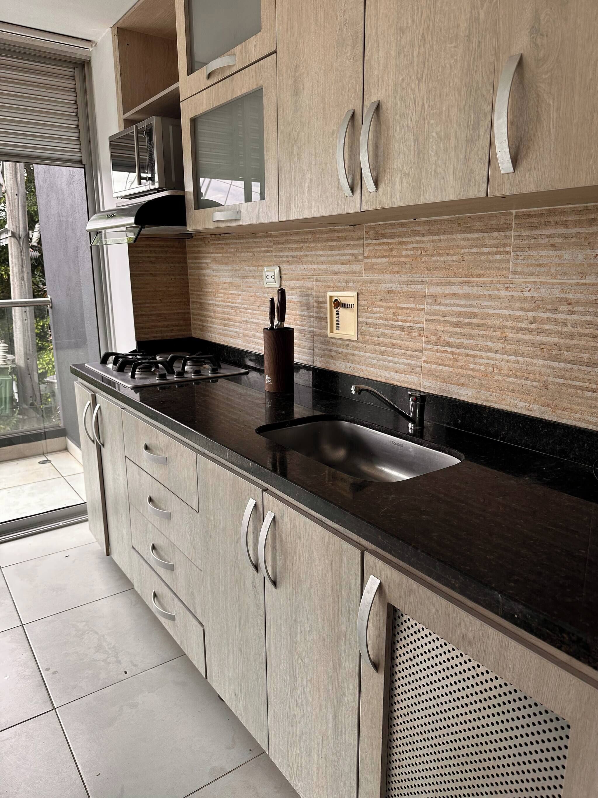 Una cocina moderna con encimera negra, electrodomésticos de acero inoxidable y armarios de madera.