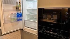 Eine moderne Küche mit integriertem Kühlschrank und Backofen, ausgestattet mit einer klaren Glastür und einer digitalen Uhr.