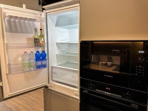 Eine moderne Küche mit integriertem Kühlschrank und Backofen, ausgestattet mit einer klaren Glastür und einer digitalen Uhr.