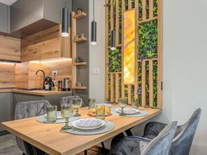Un comedor moderno con una mesa de madera dispuesta para cuatro personas, rodeada de sillas tapizadas en gris.