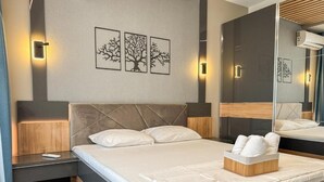Ein modernes Hotelzimmer mit einem großen Bett, einem Nachttisch und einer Wand-Klimaanlage.