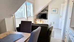 A compact living space with a dining table, sofa, and kitchenette. - Reiherweg, Apartment 4 - Beautiful 2-room vacation apartment with a south-facing balcony, quiet and (Sylt)