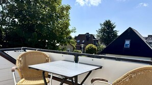 A balcony with two wicker chairs and a table, overlooking a residential area. - Reiherweg, Apartment 4 - Beautiful 2-room vacation apartment with a south-facing balcony, quiet and (Sylt)