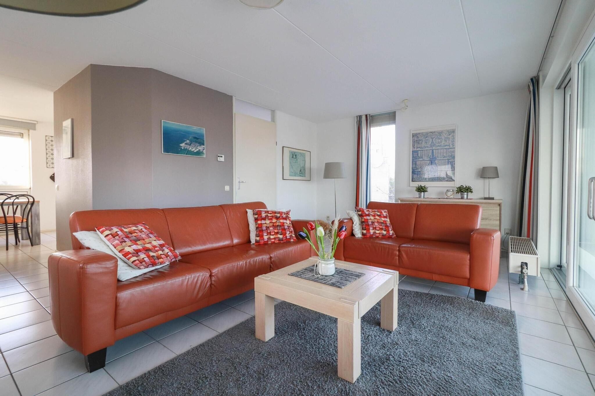 Un salon moderne avec un canapé en cuir rouge, une table basse et une vue sur l’extérieur.