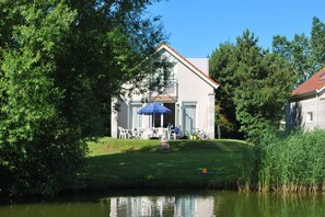 Een huis met een gazon en een vijver ervoor.