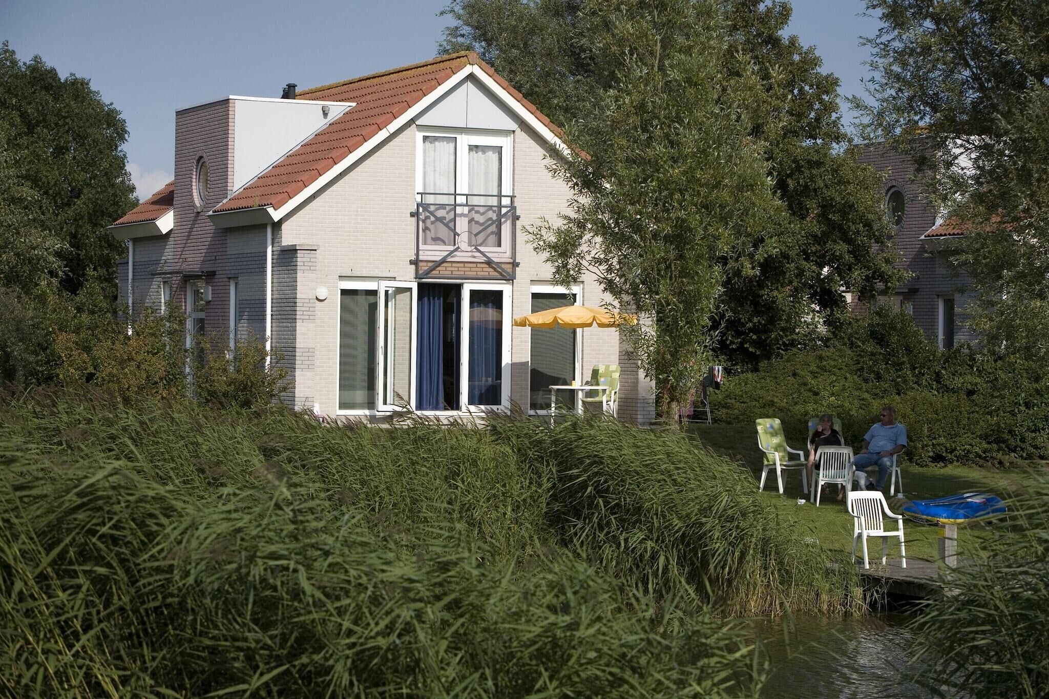 A two-story house with a balcony, a sliding glass door, and a small patio area with chairs and a table.