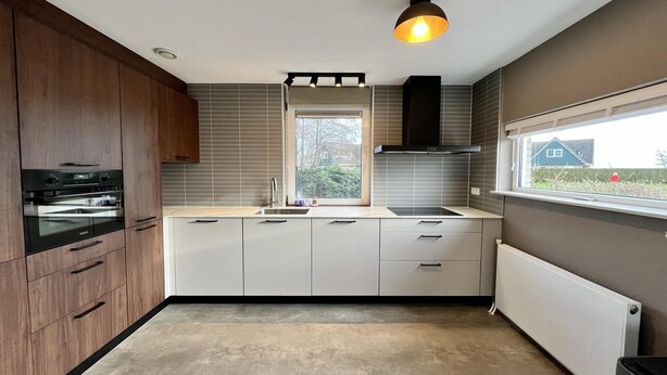 A modern kitchen with a built-in oven, a window with a view of the outside, and a pendant light. - Elegant Waterfront Bungalow for 6 (Makkum)
