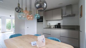 A modern kitchen with a wooden dining table, a coffee maker, and pendant lights. - Elegant Waterfront Bungalow for 6 (Makkum)