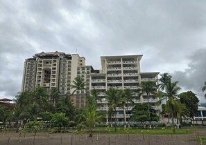 A multi-story hotel with balconies, surrounded by palm trees and a fenced garden area. - Amazing oceanfront with access Crocs Resort (Jacó)