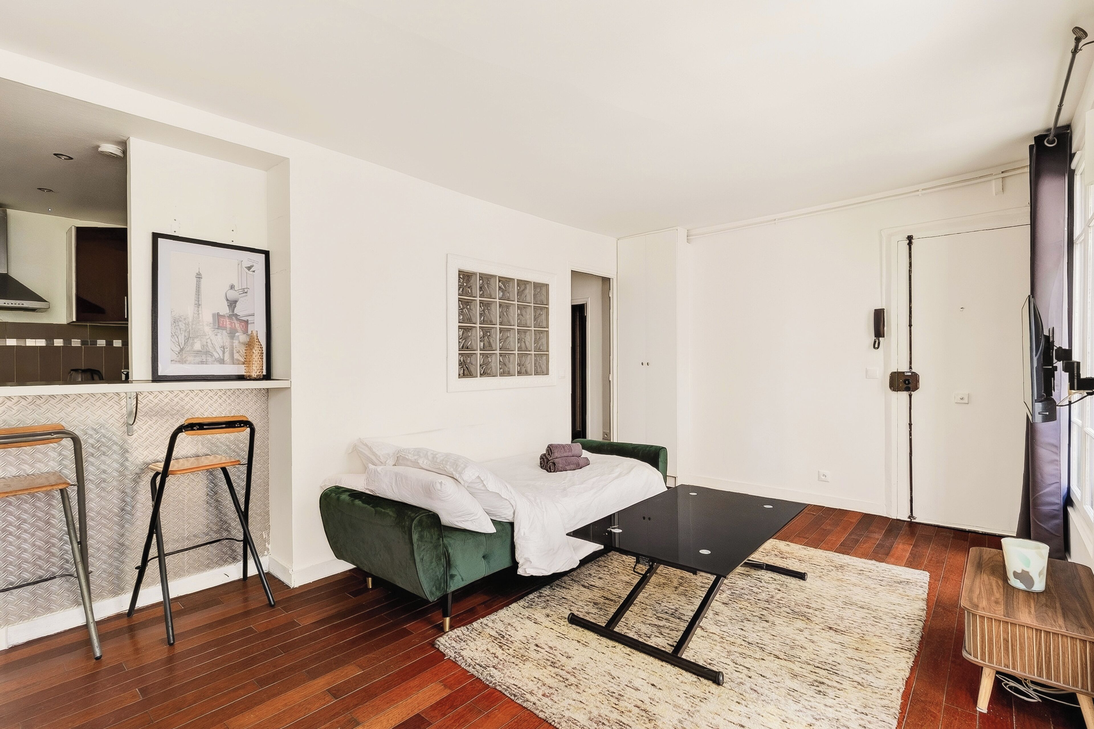 Une pièce de taille modeste comprenant un lit, une petite table, une chaise, un coin cuisine et une salle de bain.