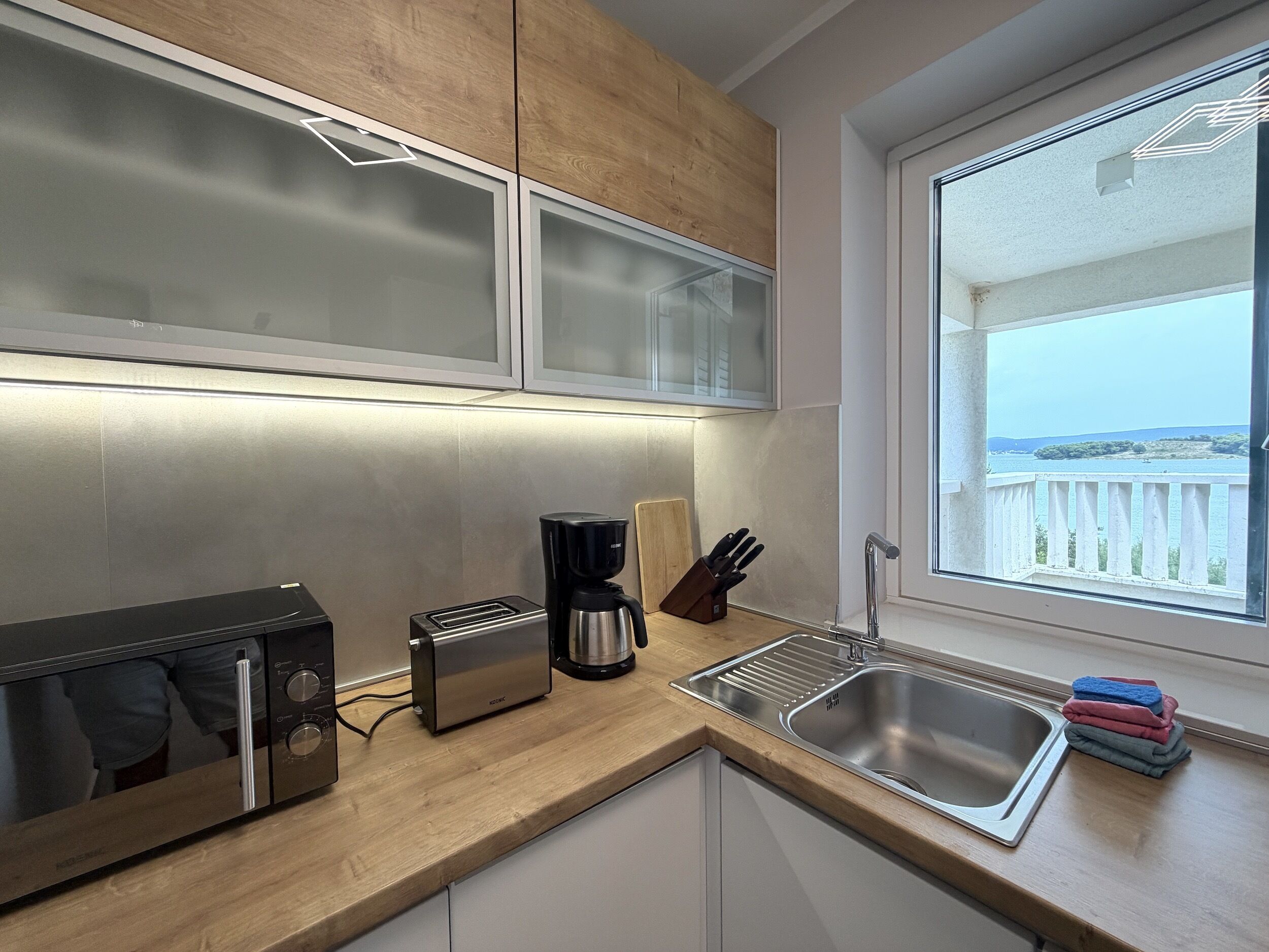 A modern kitchen with a built-in microwave, toaster, coffee maker, and a sink.
