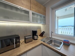 A modern kitchen with a built-in microwave, toaster, coffee maker, and a sink. - Two Bedroom Sea View Apartment Marisol (Mrljane)