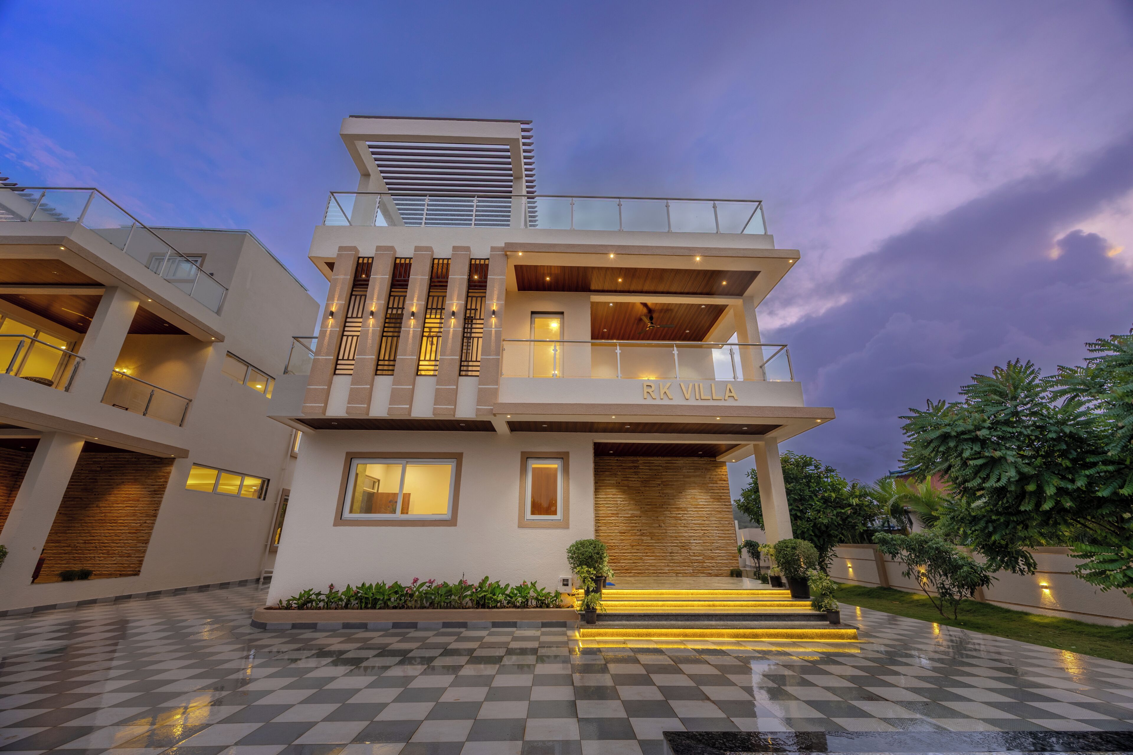 A modern multi-story villa with a checkered floor, a balcony, and a nameplate reading 'RK VILLA'.