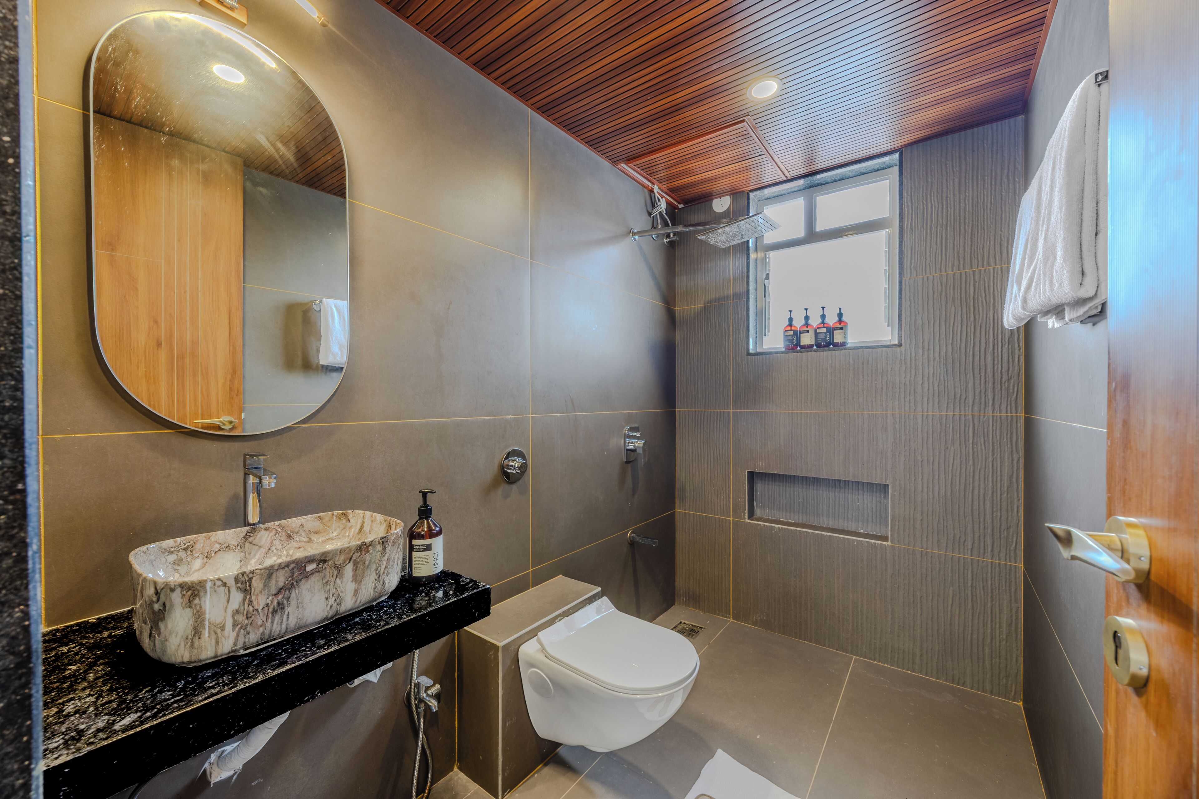 A modern bathroom with a marble sink, a toilet, and a shower area.