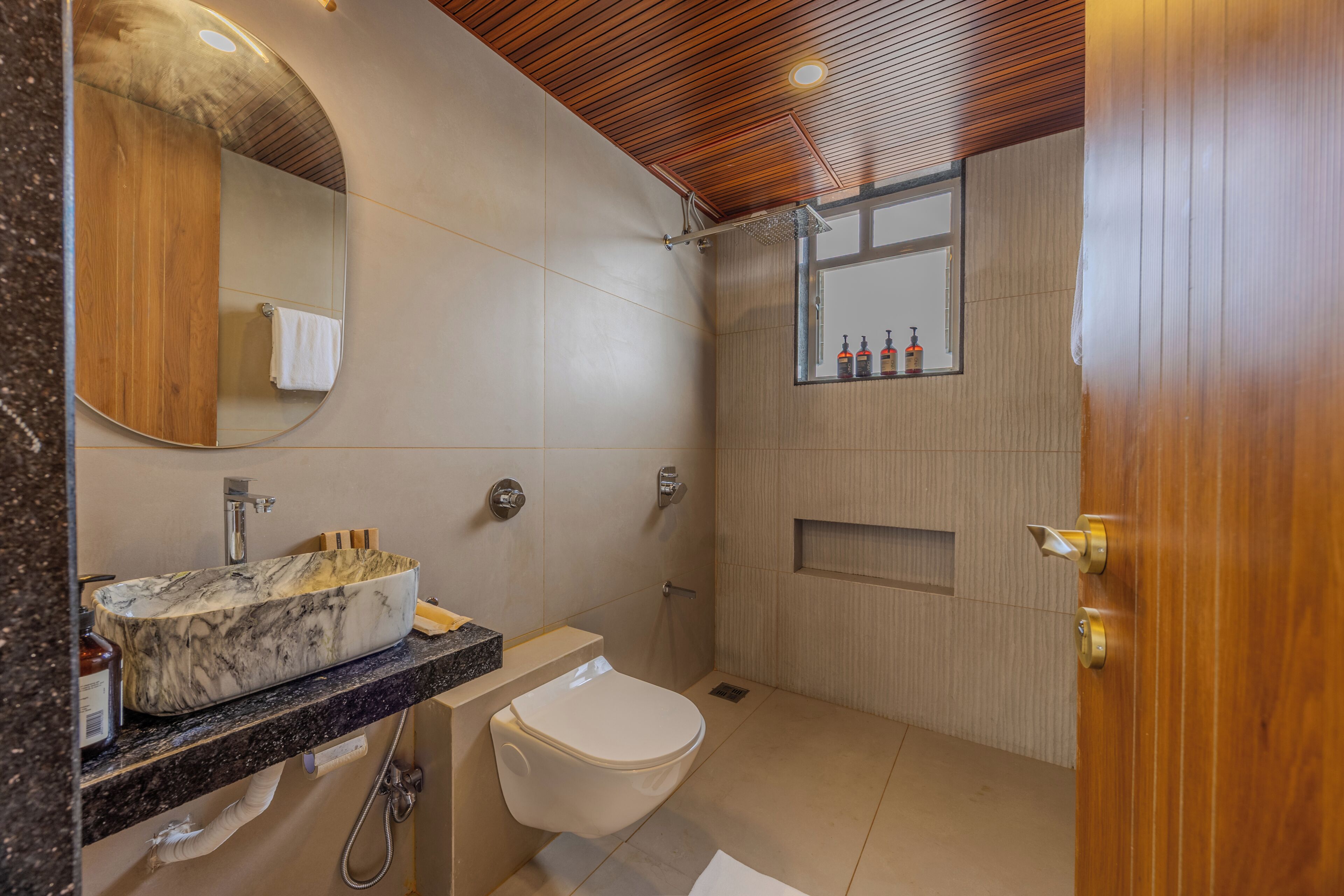 A modern bathroom with a marble sink, a toilet, and a shower area.