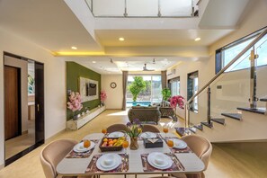 A modern dining area with a table set for four, a staircase, and a view of a pool.