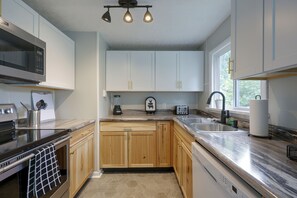 Een moderne keuken met houten kastjes, een ingebouwde magnetron, een broodrooster en een spoelbak.