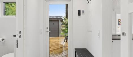 Um corredor com piso de madeira que leva a uma porta com vista para um quintal.