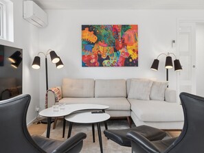 Ein modernes Wohnzimmer mit einer Eckcouch, einem Couchtisch und zwei schwarzen Sessel.