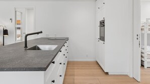 Una cocina moderna con una isla central, electrodomésticos integrados y piso de madera.