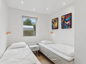 Ein Schlafzimmer mit zwei Einzelbetten, einem kleinen Tisch und zwei an der Wand hängenden Bildern.