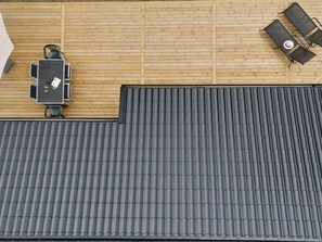 Eine Dachterrasse mit Holzboden und grauer Metallbedachung.