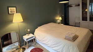 Quarto com uma cama grande, luminárias de cabeceira, um espelho, uma mesinha e uma janela com vista.