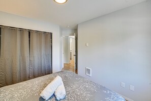 A bedroom with a bed, a bathroom door, and a hallway leading to another room. - 9 Mi to Smith Rock SP! Family Home w/ Fenced Yard (Redmond)