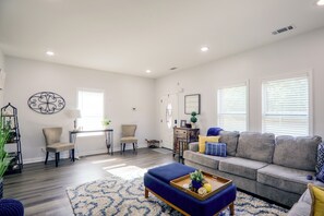 A spacious living room with a grey sofa, patterned chairs, a wooden coffee table, and a blue ottoman. - Quiet Yard, Remote Workspace! Modern Memphis Home (Memphis)