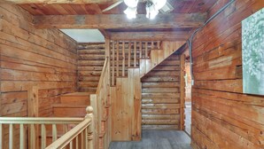Eine Holztreppe mit Handlauf führt zu einer Zwischenebene, umgeben von Holzwänden.