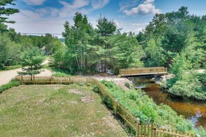 Eine Holzbrücke über einem Bach, umgeben von dichtem Grün und Bäumen.