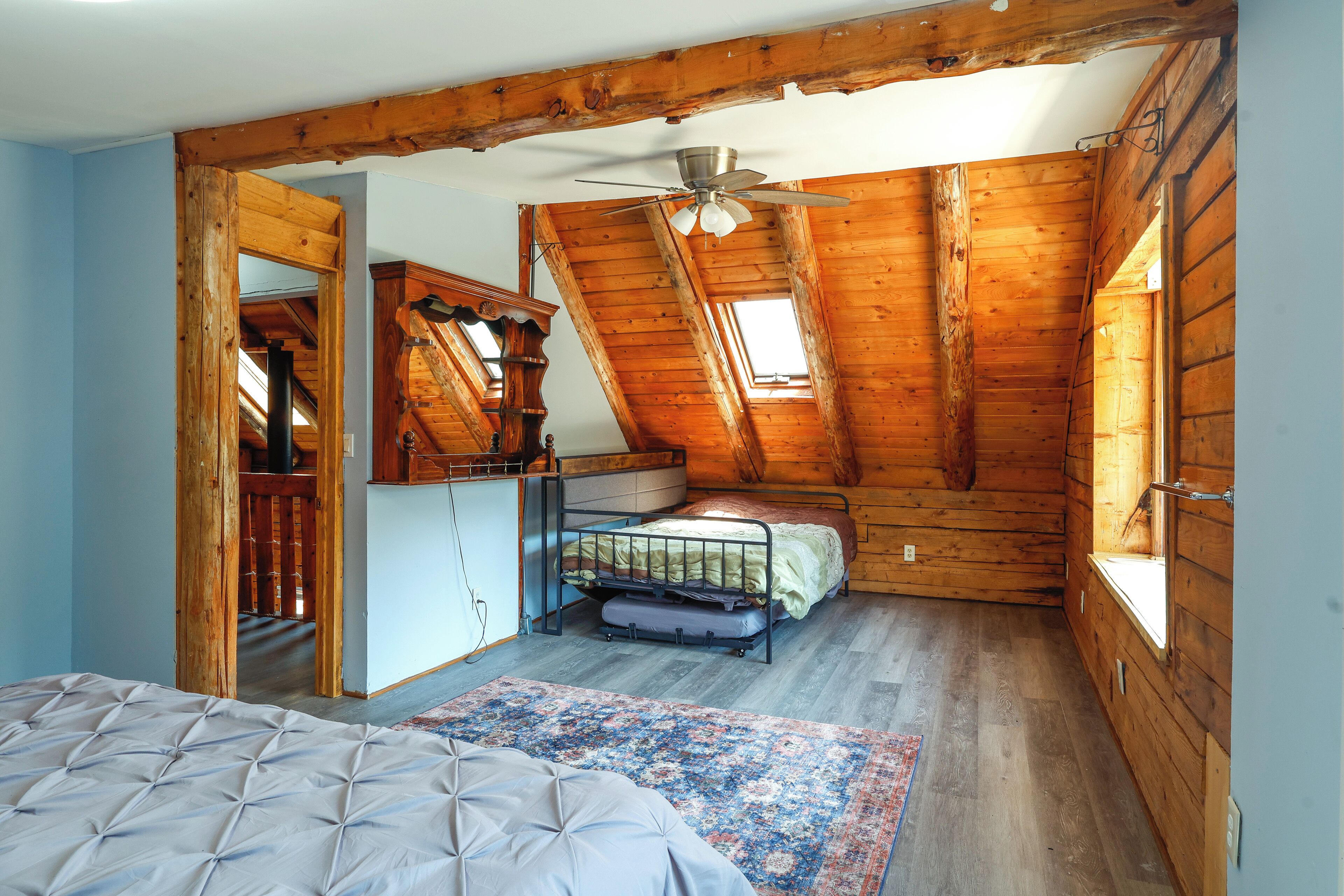 Een slaapkamer met een stapelbed, een plafondventilator, een raam en een houten plafond.