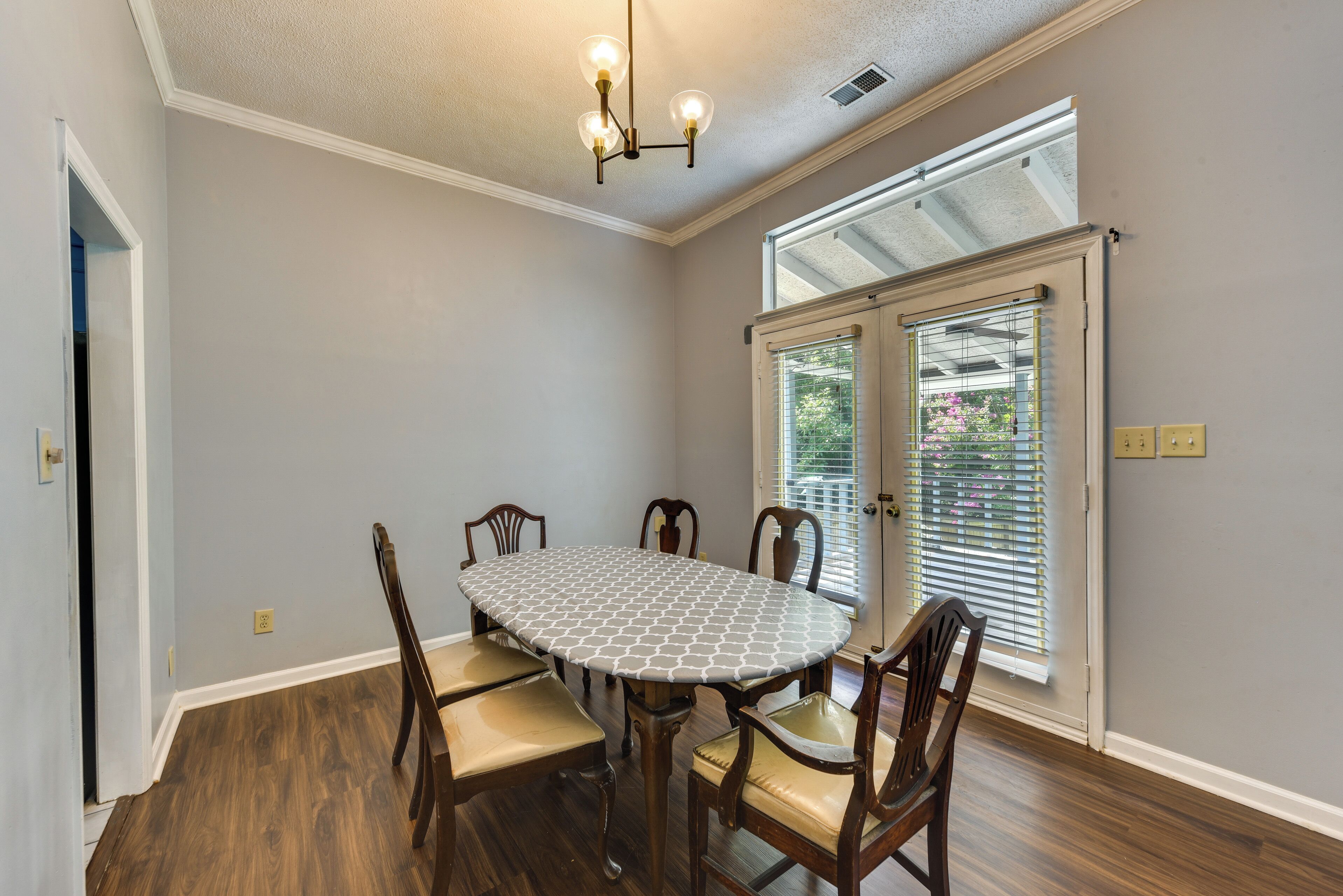 A dining room with a round table, wooden chairs, and a ceiling light fixture.