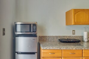 Eine Küche mit einer Mikrowelle auf dem Kühlschrank, einer Kaffeemaschine auf der Arbeitsplatte, Holzausbau und einer Arbeitsplatte aus Granit.