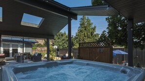 A hot tub under a covered patio with outdoor furniture and a wooden fence in the background. - Private Pool & Basketball | Spacious 3BR Sleeps  9 (Wenatchee)