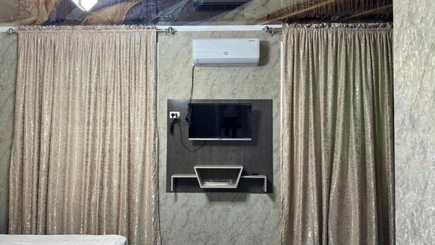 Habitación con aire acondicionado, televisor y una pequeña estantería.