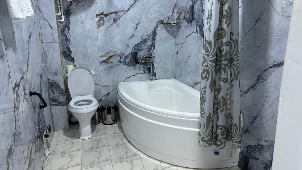 Et badeværelse med toilet, badekar og marmorvægge.