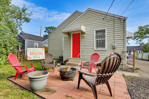 A small house with a designated smoking area sign, outdoor seating with chairs, and a fire pit. - 4 Mi to Downtown Columbus! Updated Home w/ Yard (Columbus)