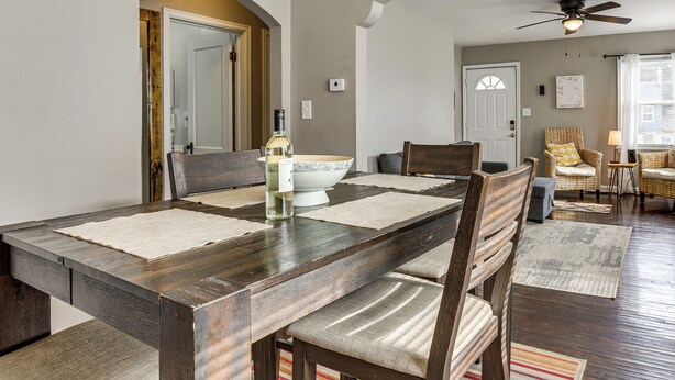 Un comedor con una mesa de madera, sillas y una botella de vino.