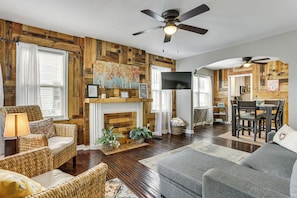 Un salon avec une cheminée, des murs en bois, un ventilateur de plafond et un téléviseur.