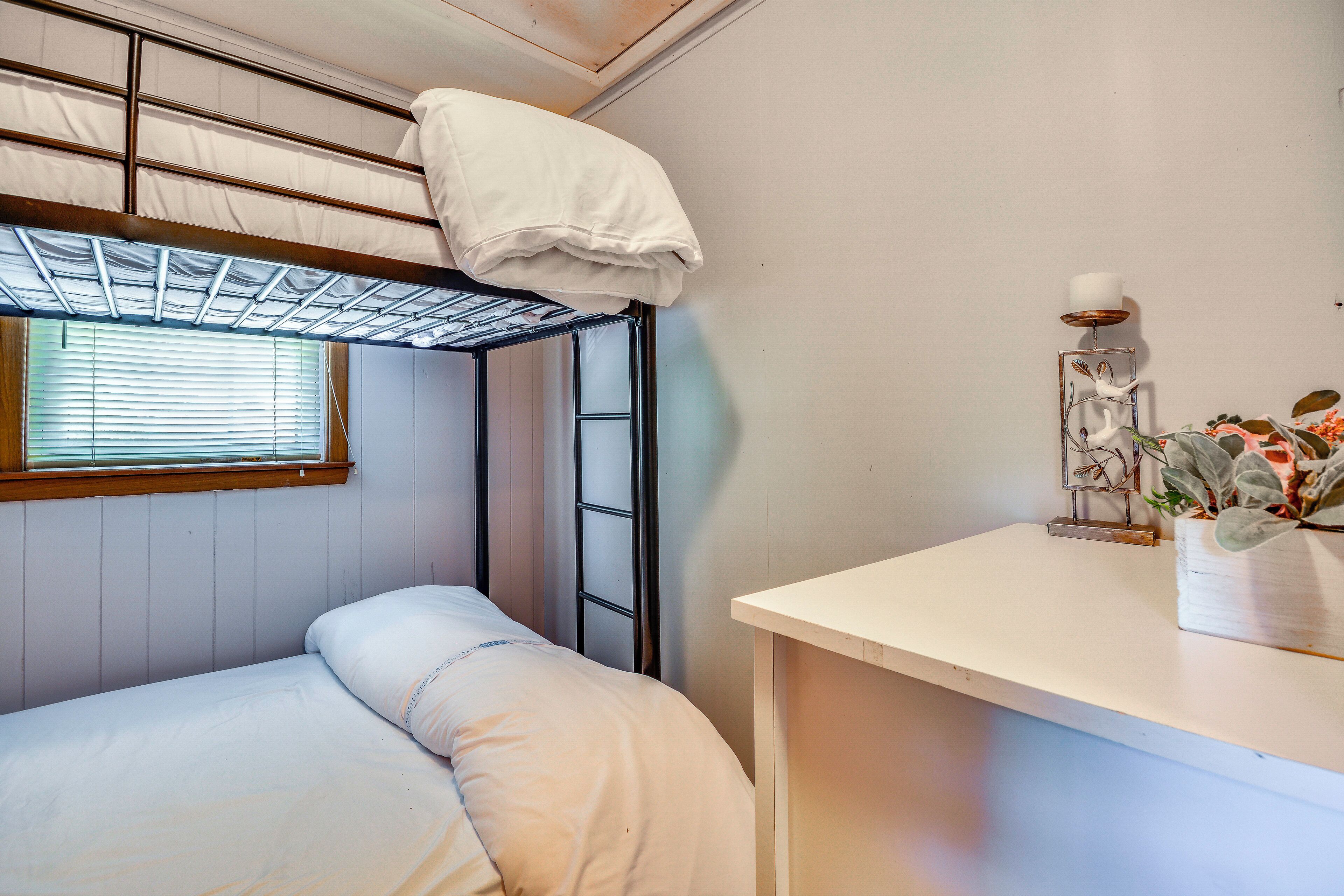 Een stapelbed met een raam, een nachtkastje met een decoratief object, en een wandplank.