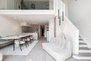 A modern interior with a dining area, sofa, and staircase. - Spacious Duplex in Knokke Centre (KNOKKE)