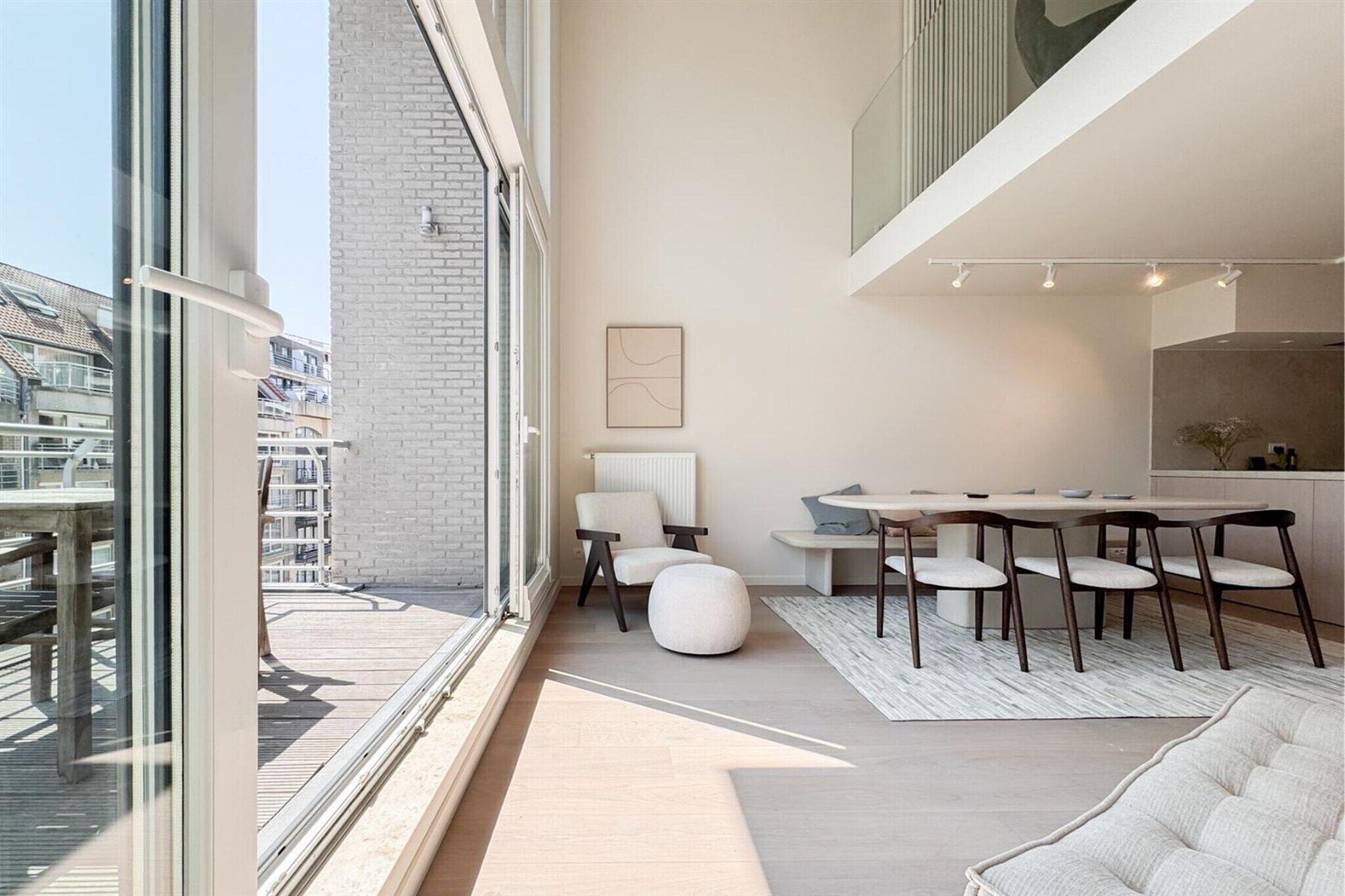 Een modern interieur met een eethoek, een bank en stadszicht door grote ramen.