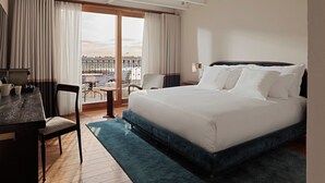 A hotel room with a large bed, a desk with chairs, and a view of the city through the window. - Nazenin Hotel (Istanbul)