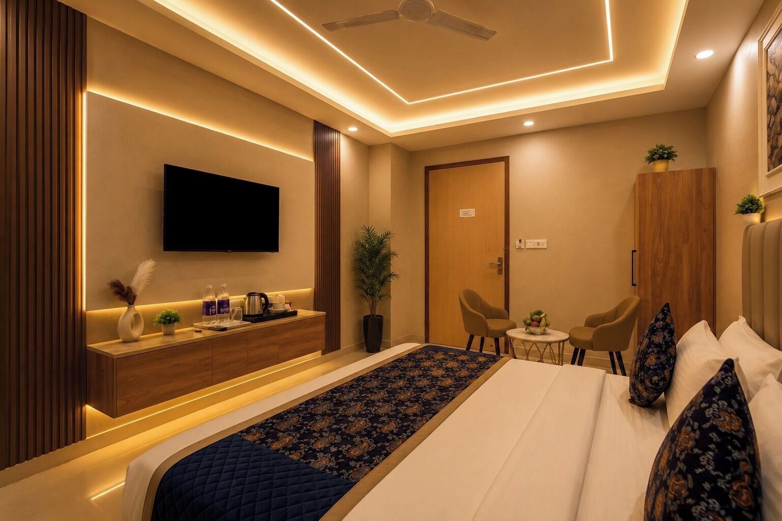 A modern hotel room with a bed, a TV, a desk, and a small seating area.