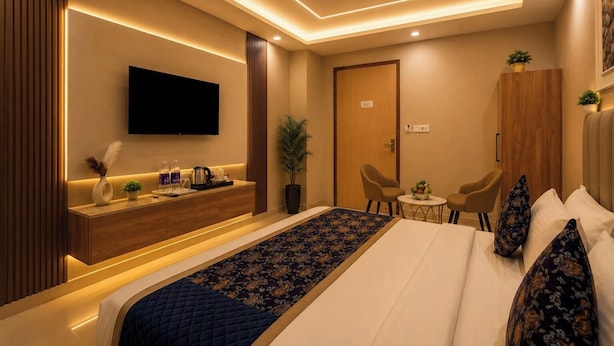 A modern hotel room with a bed, a TV, a desk, and a small seating area. - Hotel Smart International (New Delhi)